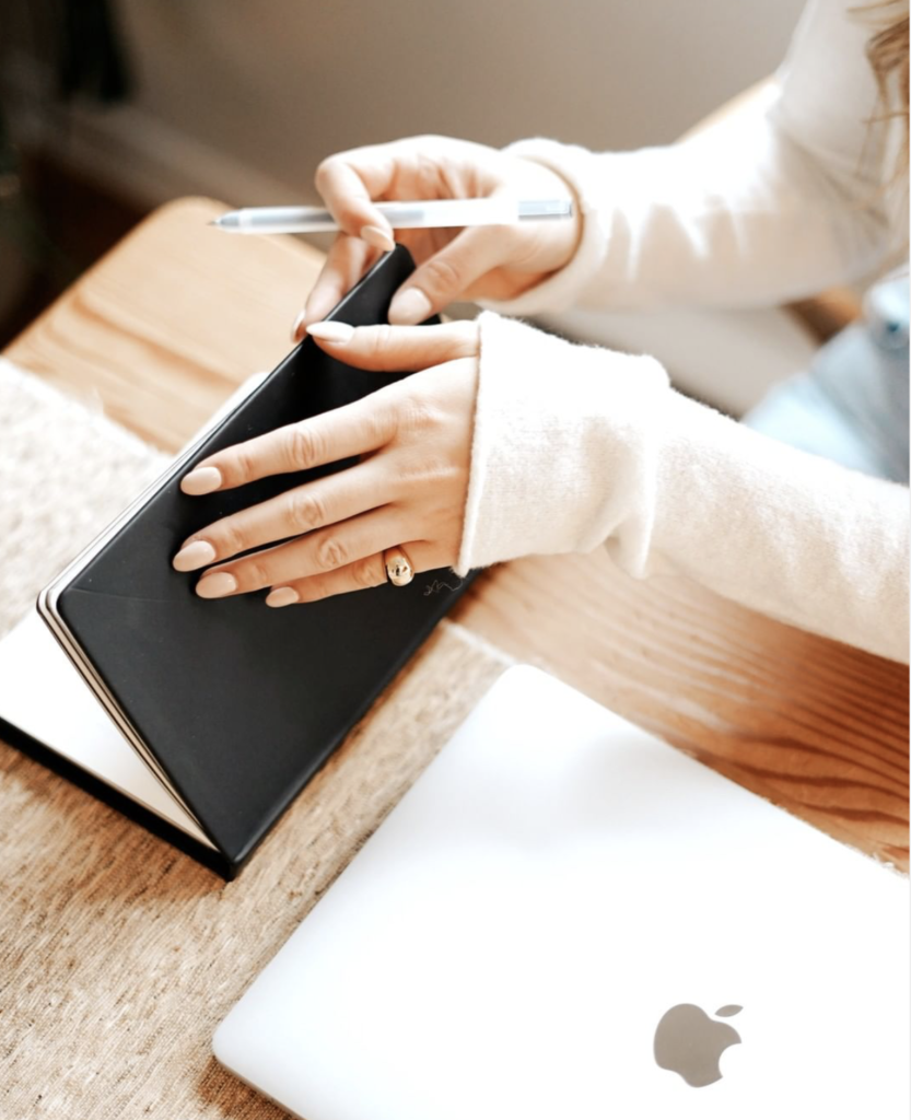 woman's hands opening black leather journal for self-education