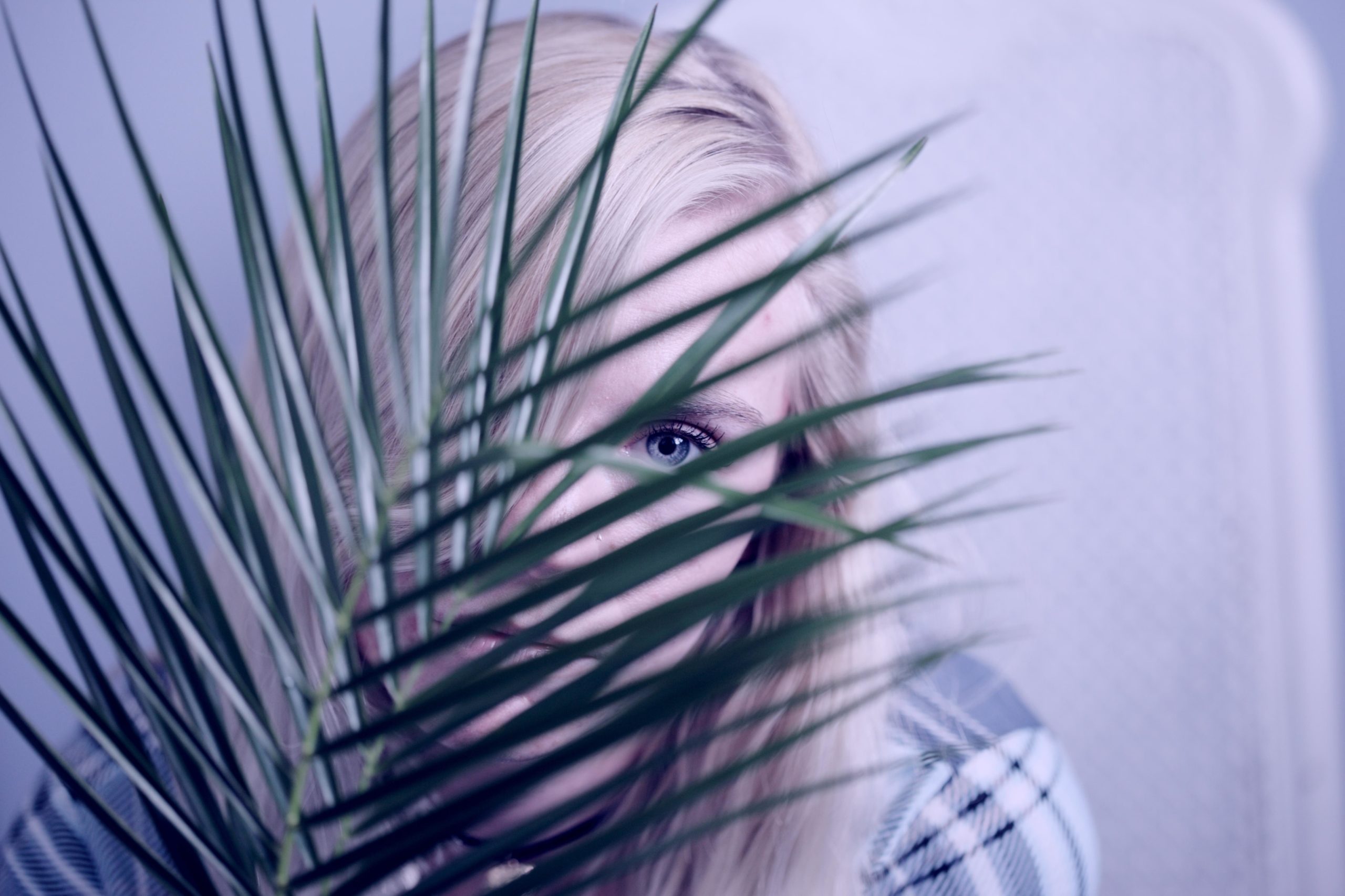 shy woman hiding behind palm frond