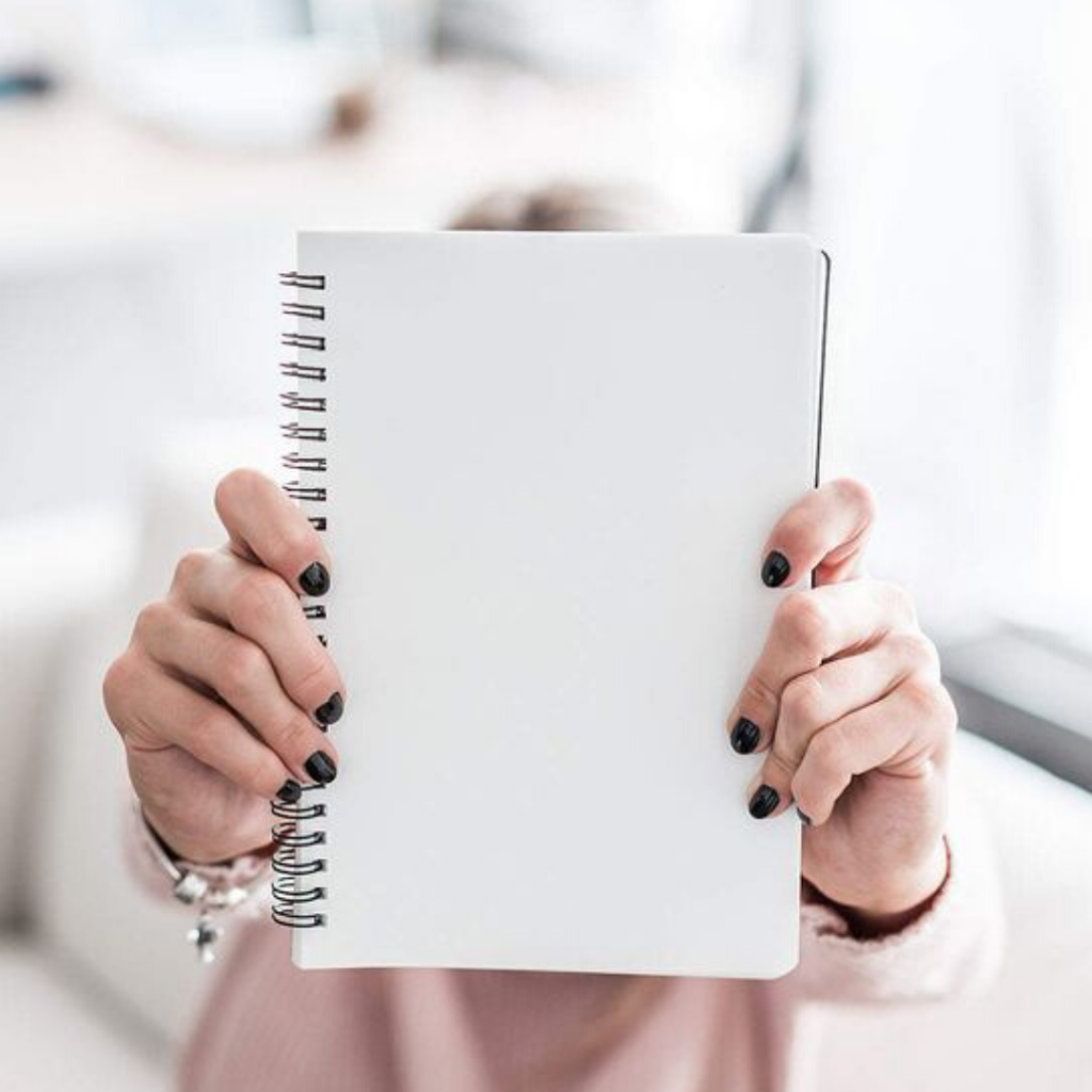 woman holding blank spiral notebook to journal about how to reach full potential