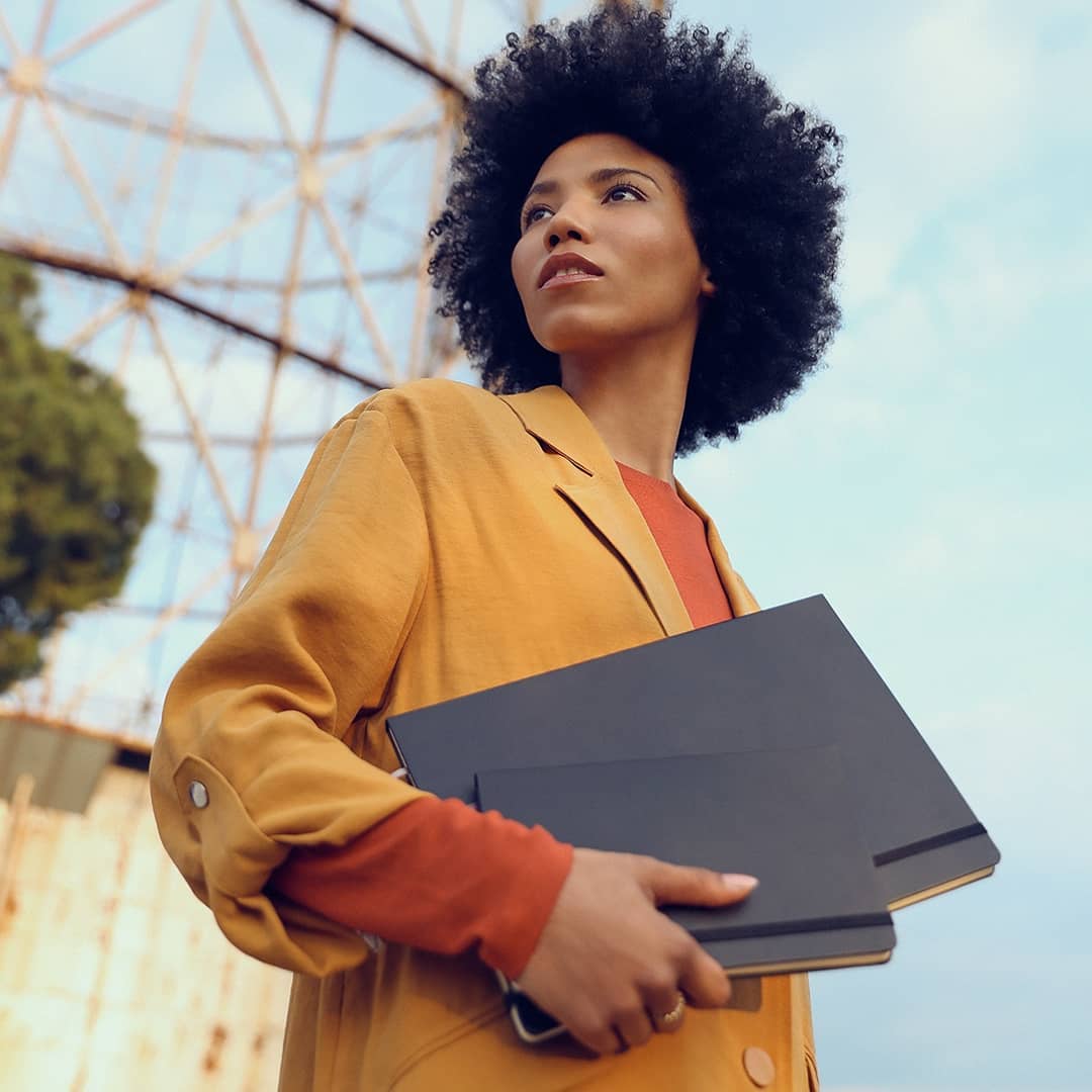 woman holding two black notebooks