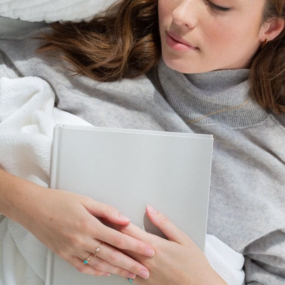 sleeping woman in grey sweater holding journal