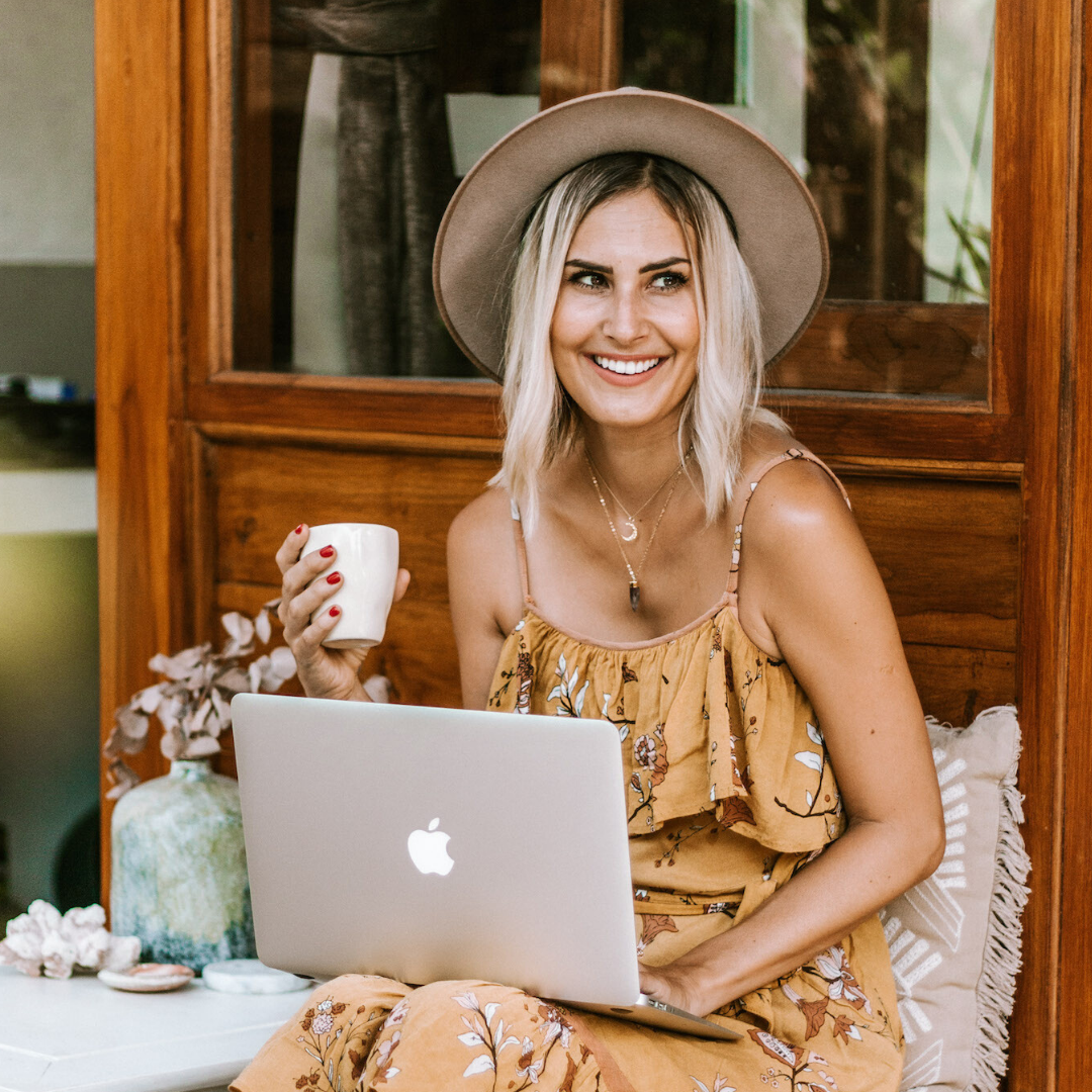 blonde woman in yellow dress working on laptop